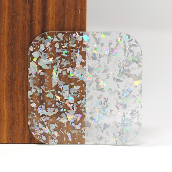 Iridescent Silver Confetti acrylic sheet ??? 3mm clear cast acrylic with metallic silver foil flakes, ideal for laser cutting, signage, jewelry making, and decorative craft projects. Sample shown against wood and white background.