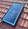 Solatube Premium Fixed Skylight with black frame installed on a terracotta tiled roof, reflecting blue sky.
