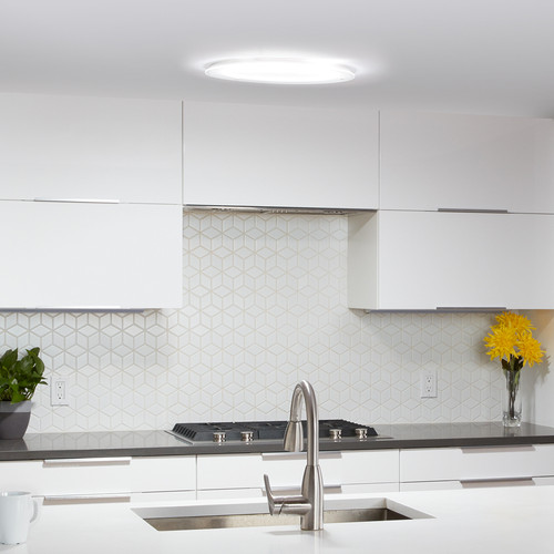Flush-mount, round skylight accessory on a white kitchen ceiling. Flush-mount, round skylight accessory on a white kitchen ceiling.
