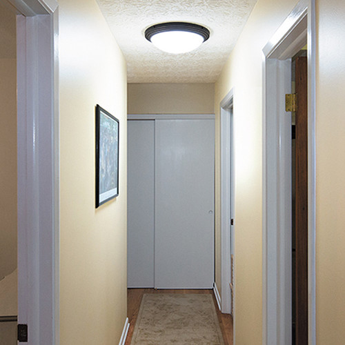 Hallway illuminated by a ceiling-mounted AuroraGlo Glass Fixture with a black trim.
