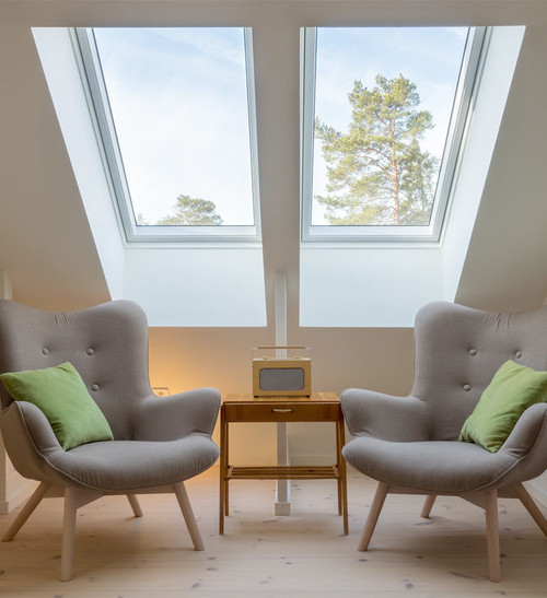 Two Solatube Premium Fixed Skylights illuminate an attic room with armchairs.