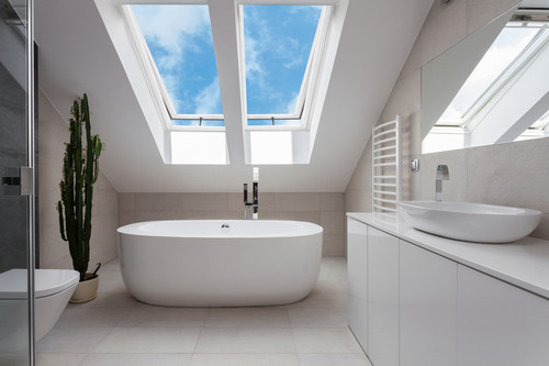 Bright bathroom featuring two Solatube Solar-Powered Fresh Breeze Skylights showcasing a blue sky view.
