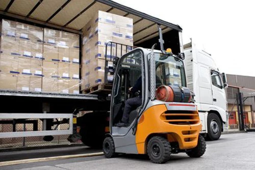Forklift unloading shipping inventory from heavy container vehicle truck
