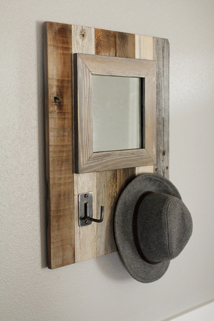 Rustic barnwood wall mirror with integrated hooks, handcrafted from reclaimed wood slats for a functional and stylish entryway accent.