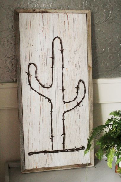 Rustic whitewash barnwood cactus wall décor handcrafted from reclaimed wood and barb wire, creating a bold western-inspired statement piece.