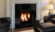 Q1 gas fireplace with black enameled liner and log set burning in a living room