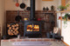 Encore stove in the middle of a brick hearth with stove accessories