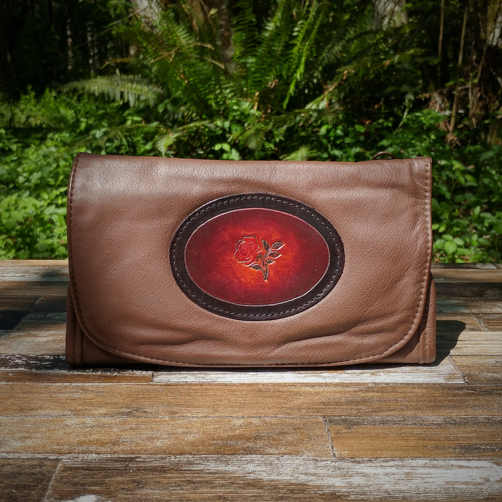 Brown Strapped Wallet with Tooled Rose Medallion.

Combines the elegant look and quality of soft leather with a Tooled Leather Medallion on the front flap.