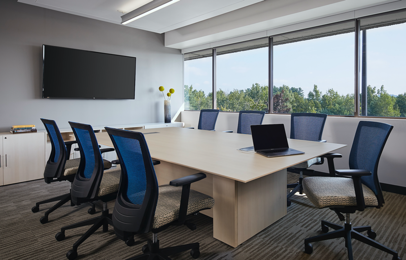 Corporate boardroom with a large conference table and blue task chairs, furnished by Orlando Office Furniture