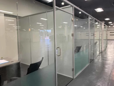Glass-front private offices with aluminum frames and glass doors in a dealership office space