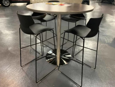 Round high-top table with black stools on the showroom floor of an Orlando auto dealership