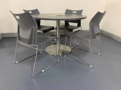 Round break room table with gray chairs and a chrome base for dealership staff