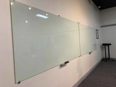 Wall-mounted glass marker boards in a dealership training or meeting room