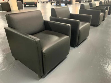 Row of black leather lounge chairs on the dealership showroom floor