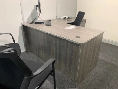 L-shaped laminate desk with guest chairs in a dealership private office