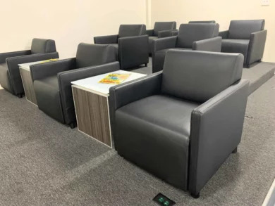 Black leather lounge chairs with wood-grain side tables in an Orlando dealership customer waiting area
