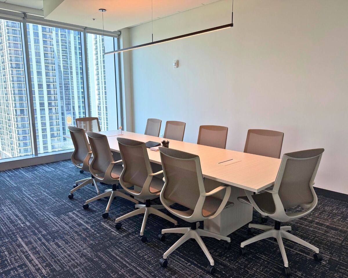 Ten-seat conference table with mesh task chairs and linear pendant light in Orlando high-rise office