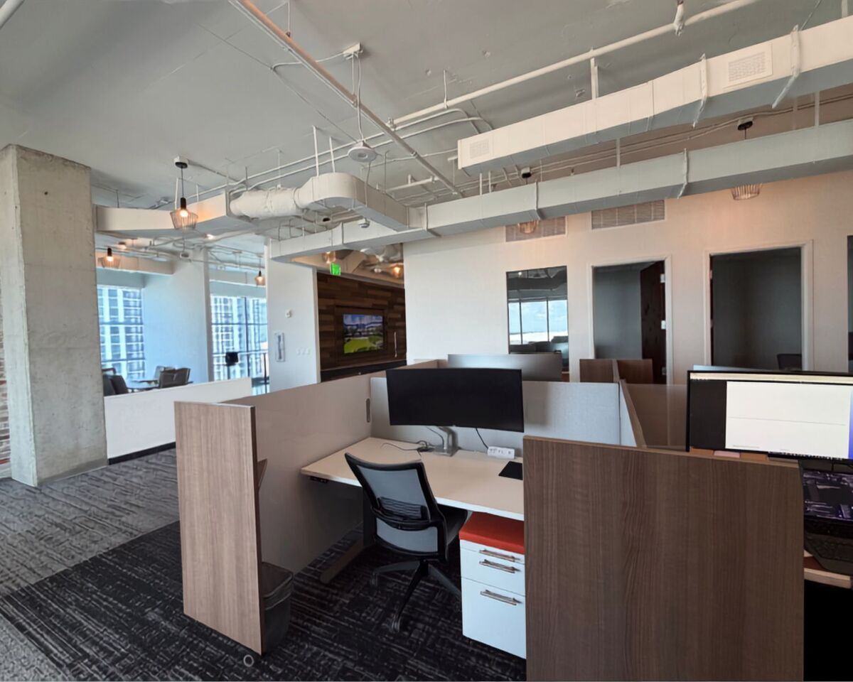 Height-adjustable workstations with monitor arms and wood-tone dividers in commercial real estate office