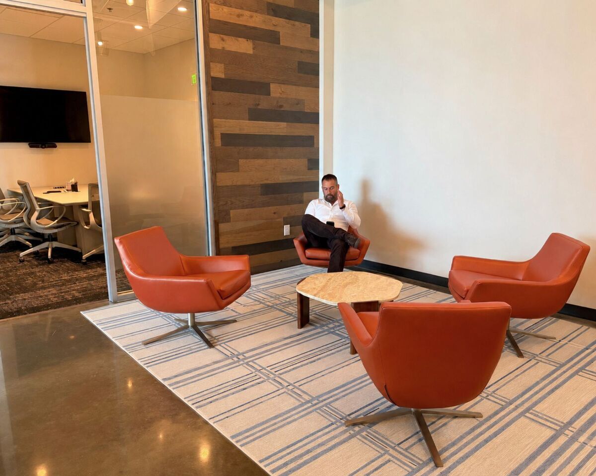 Lounge seating with orange swivel chairs and stone-top table outside glass conference room
