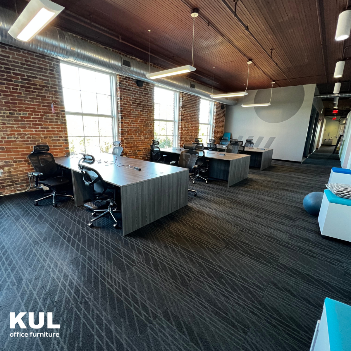 Wide view of an Orlando open office with benching workstations, mobile pedestals and a breakout seating area