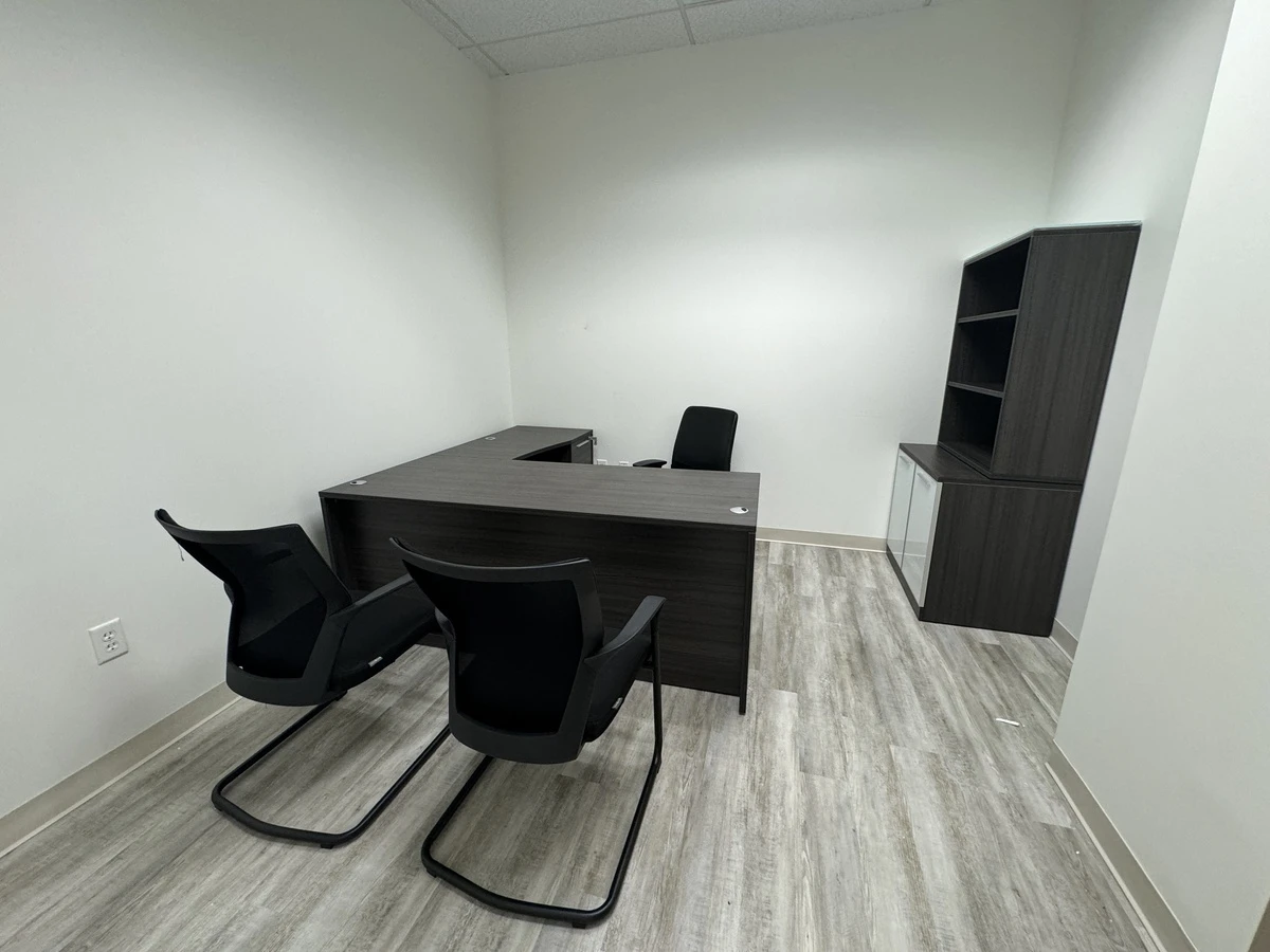 Private office with charcoal L-shaped desk, bookcase hutch, credenza, and two black guest chairs