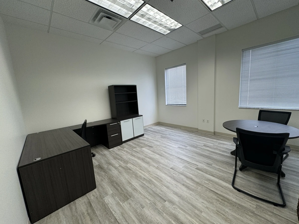 Executive office with L-shaped desk, hutch, storage credenza, and round meeting table