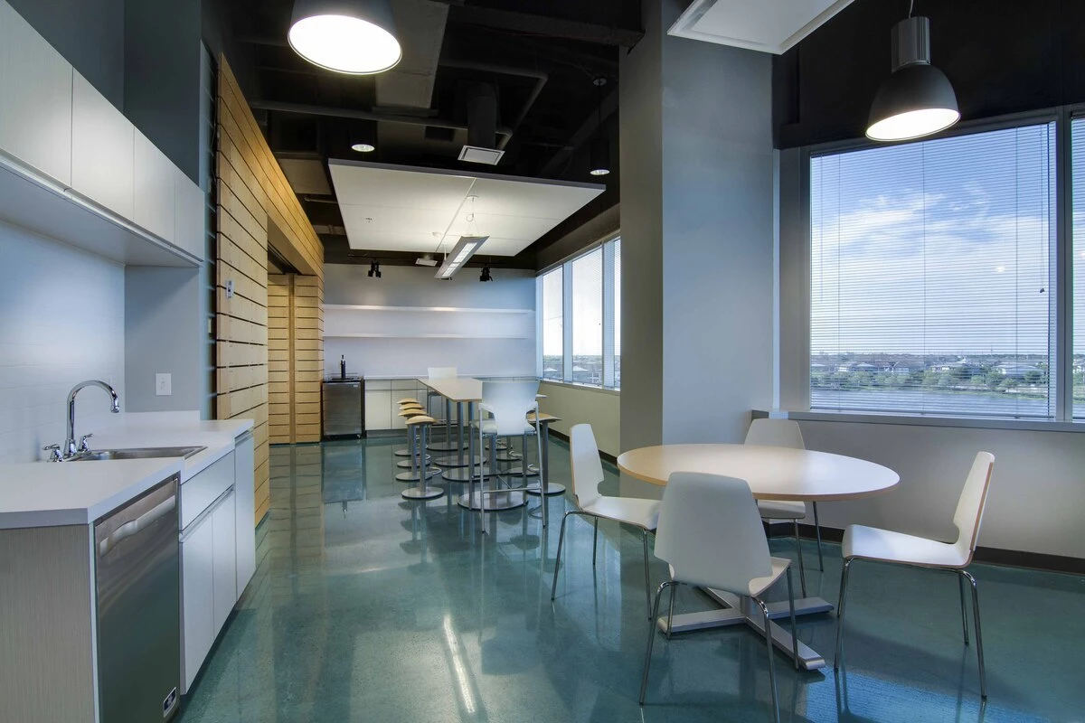 Kitchenette with round café table, white chairs, and bar-height seating by the windows