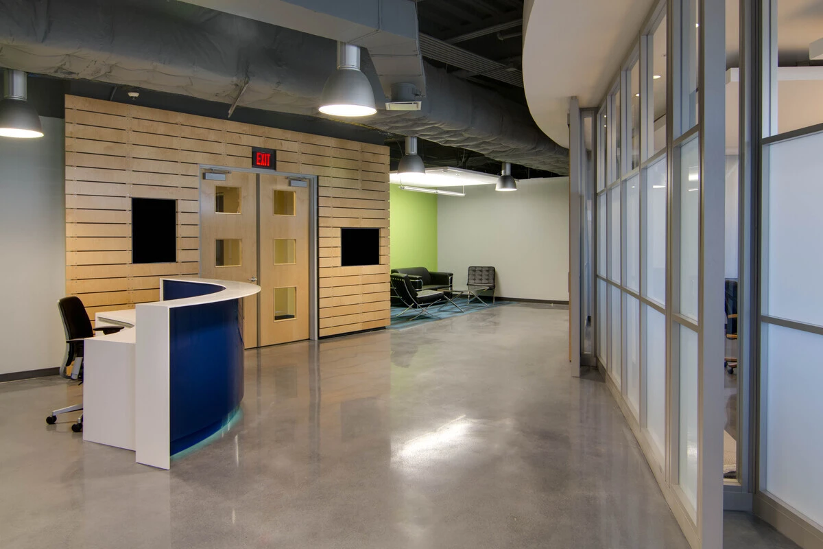 Reception desk with curved blue and white front, wood slat wall, and lounge seating
