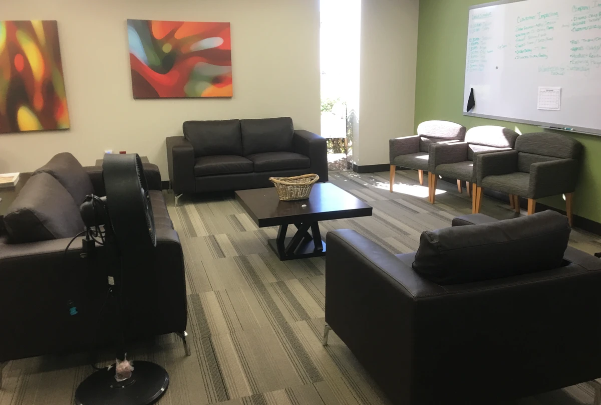 Lounge area with black leather sofas, upholstered guest chairs, and espresso coffee table