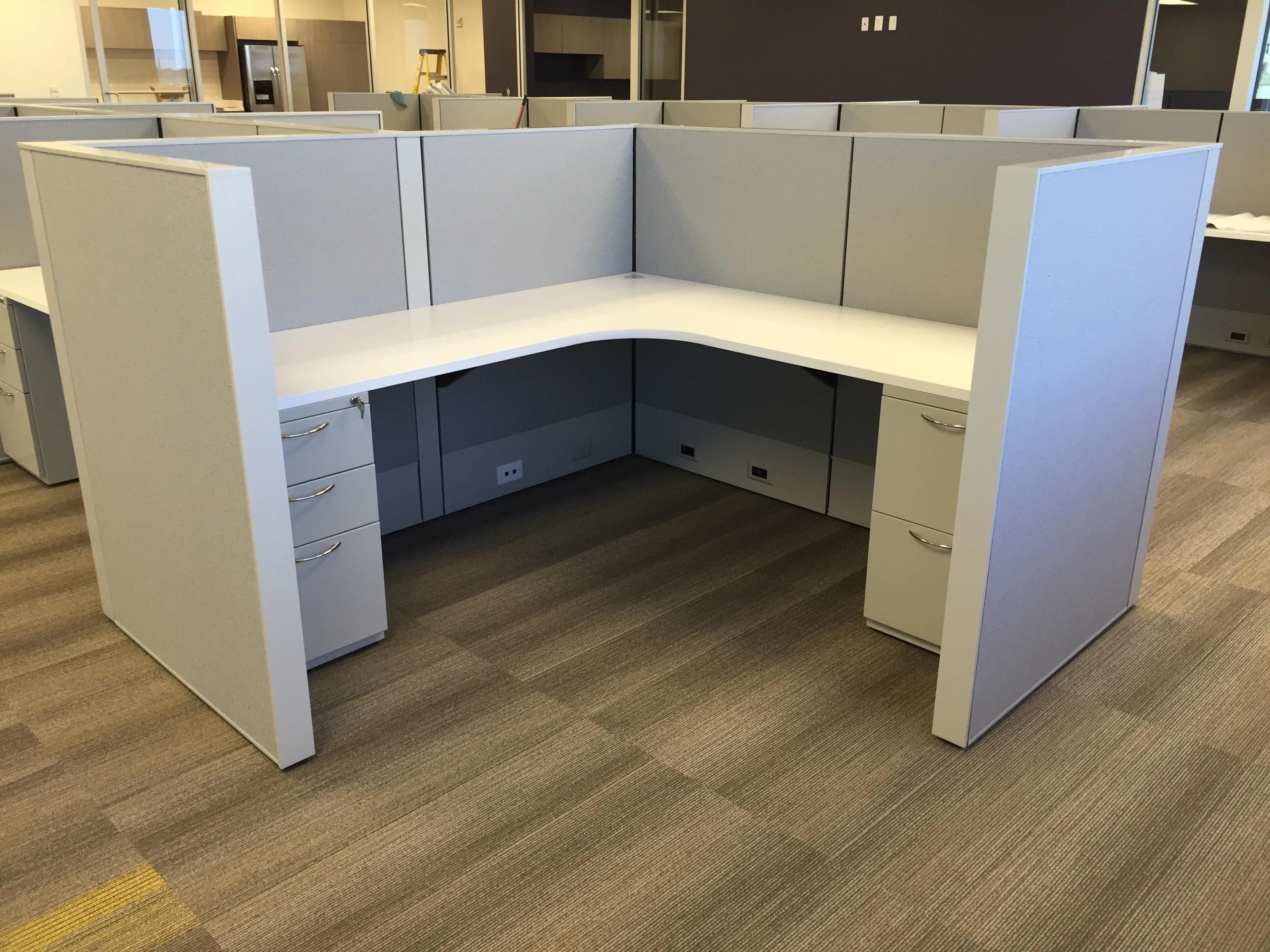 L-shaped workstation with gray panels, pedestal file drawers, and open floor plan