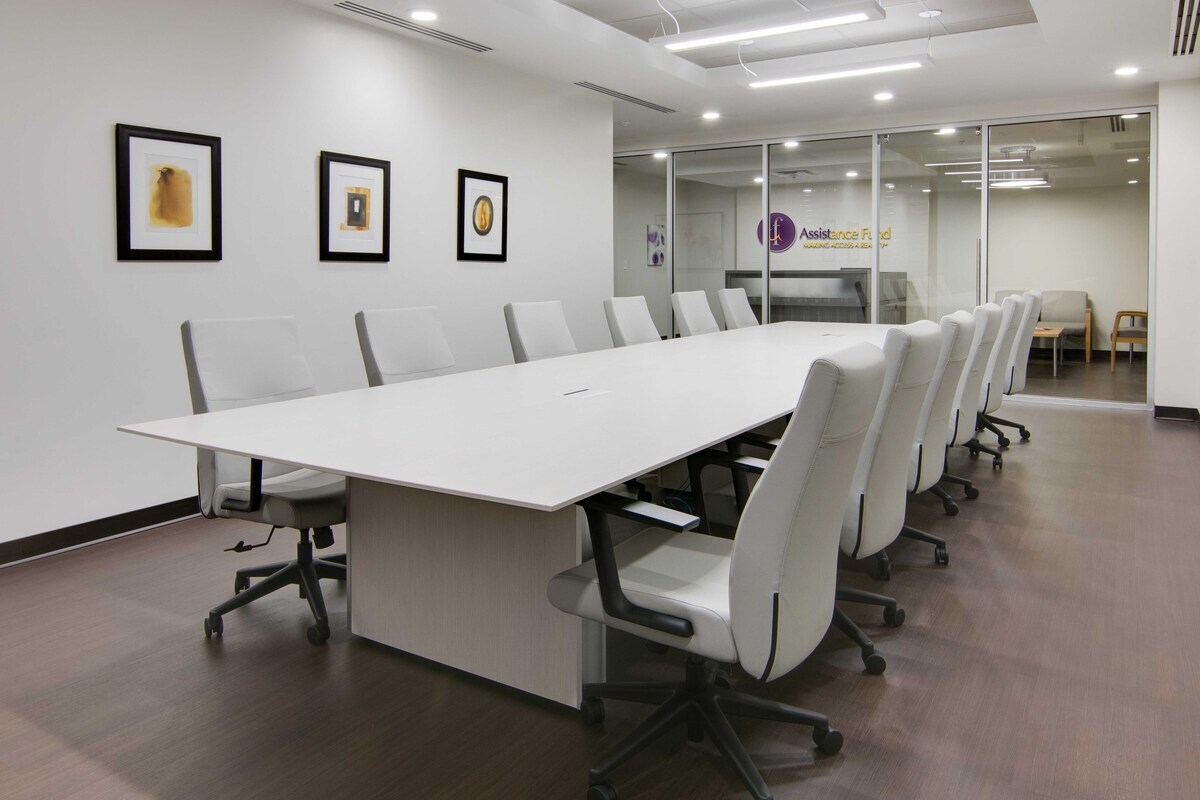Long white conference table with white high-back chairs and framed art