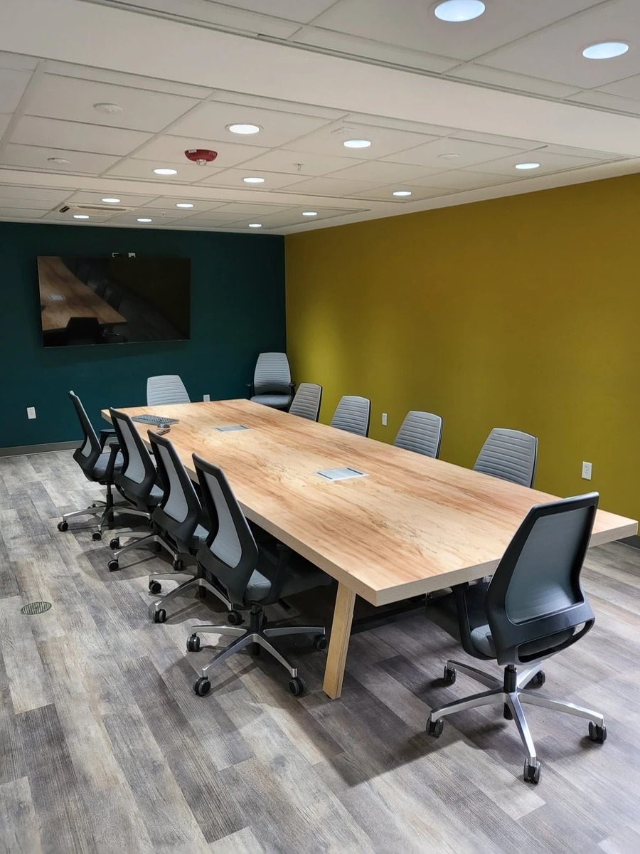 Wood conference table with power ports and gray mesh-back chairs in a Central Florida law office