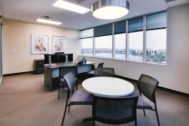 Private office with desk, dual monitors, and round meeting table with upholstered chairs, Orlando