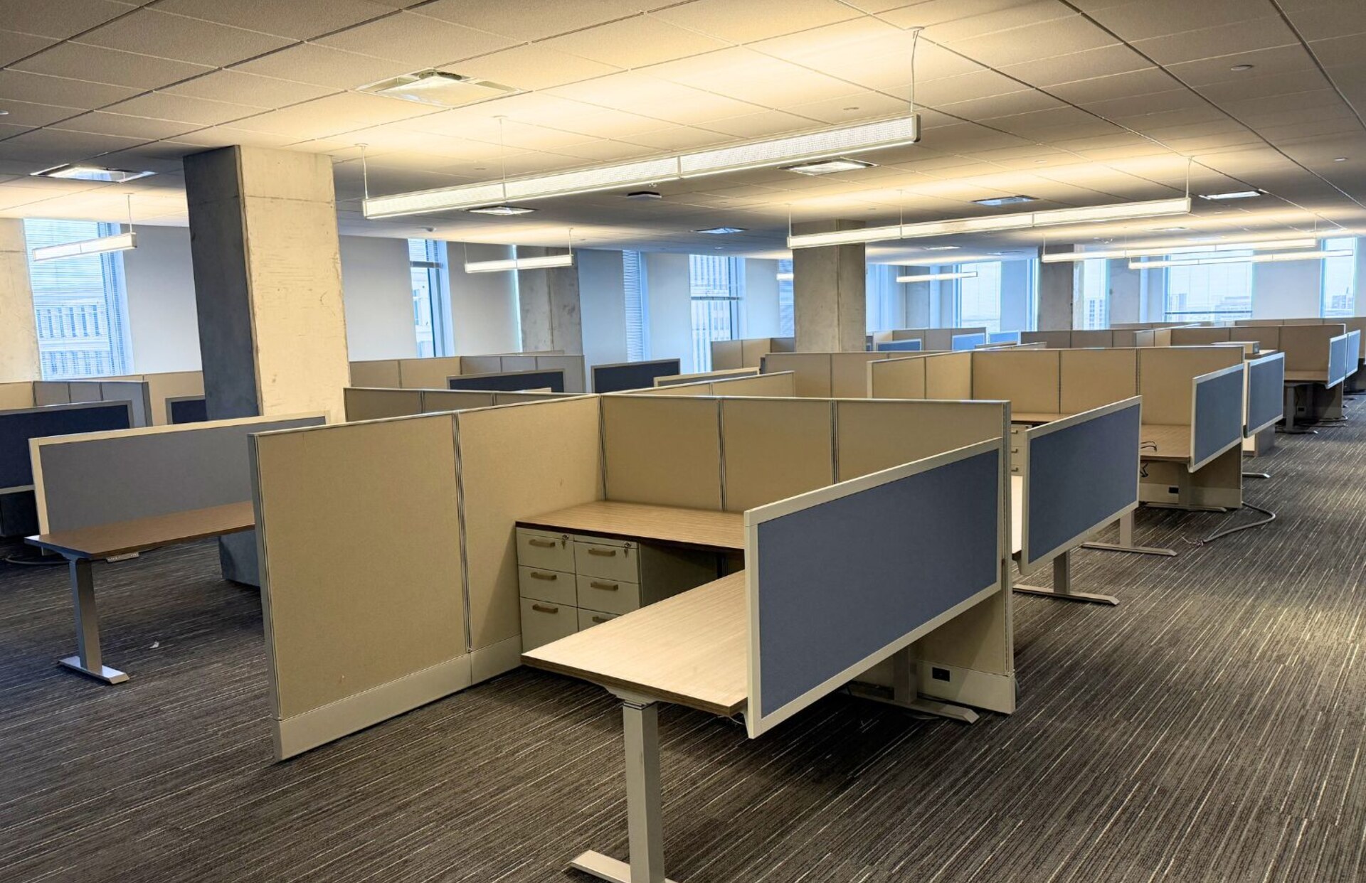 Installed Orlando office floor of cubicle workstations with height adjustable desks, blue privacy screens, and file pedestals