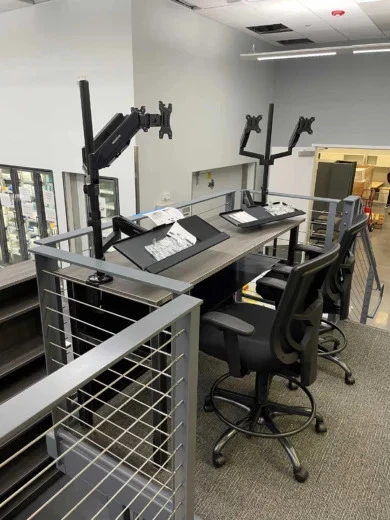 Standing-height desk with monitor arms and tall ergonomic task chairs on a raised platform, Orlando