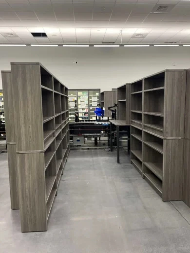 Gray woodgrain open bookcases forming storage aisles in a pharmaceutical facility, Orlando