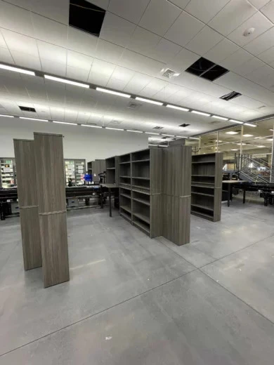 Rows of woodgrain open shelving and work tables across a Central Florida pharmaceutical workspace