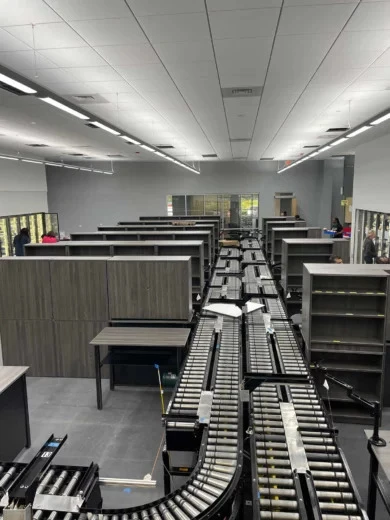 Woodgrain storage units and work tables alongside conveyor lines in an Orlando pharmaceutical facility