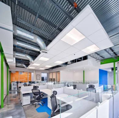 Open office workstations with gray panels, glass toppers, and mesh task chairs under exposed ductwork, Orlando