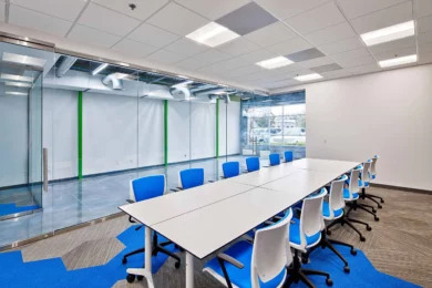 Conference room with long white table and blue chairs on blue and gray carpet, Central Florida tech office