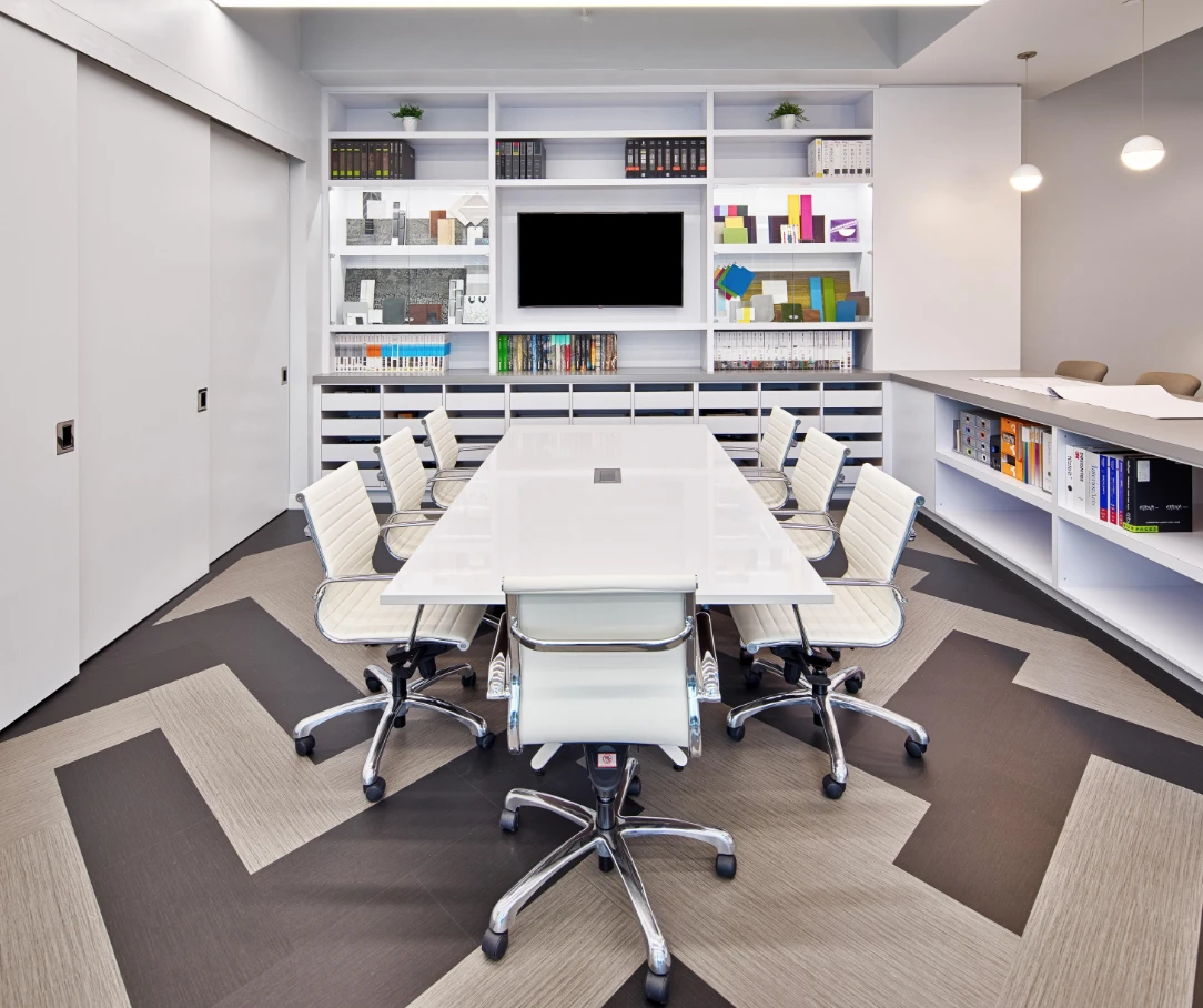 White conference table with white ergonomic chairs and built-in material library shelving in an Orlando architectural firm office