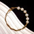 bracelet moitié jonc, moitié perle en plaqué or avec des perles baroques blanches en forme de pomme de terre.