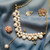 collier avec chaîne plaquée or et pendentif en forme de V orné de perles blanches d'eau douce, montrant la variété de tailles de perles utilisées pour créer le motif, détail du pendentif suspendu, montrant la perle unique en son centre.