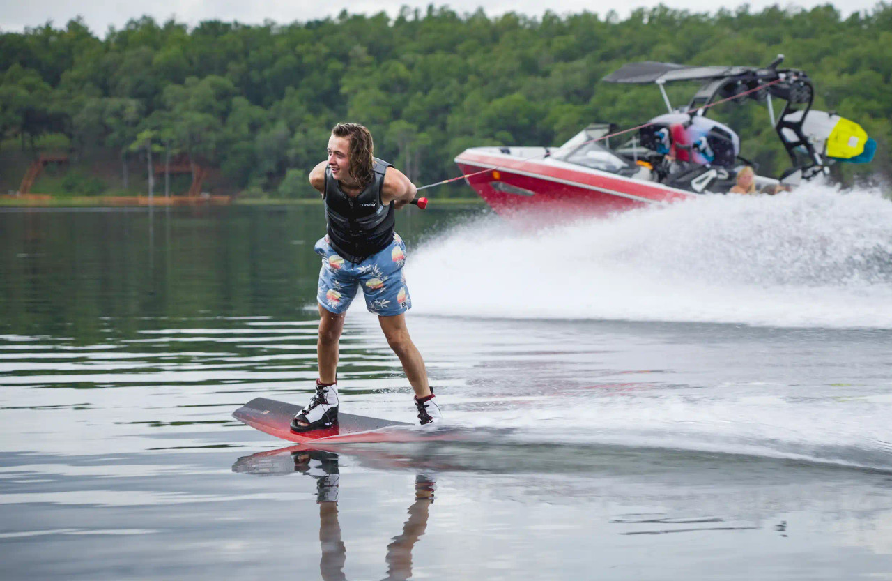 Wakeboarder riding behind boat with Connelly Pure and Venza Bindings