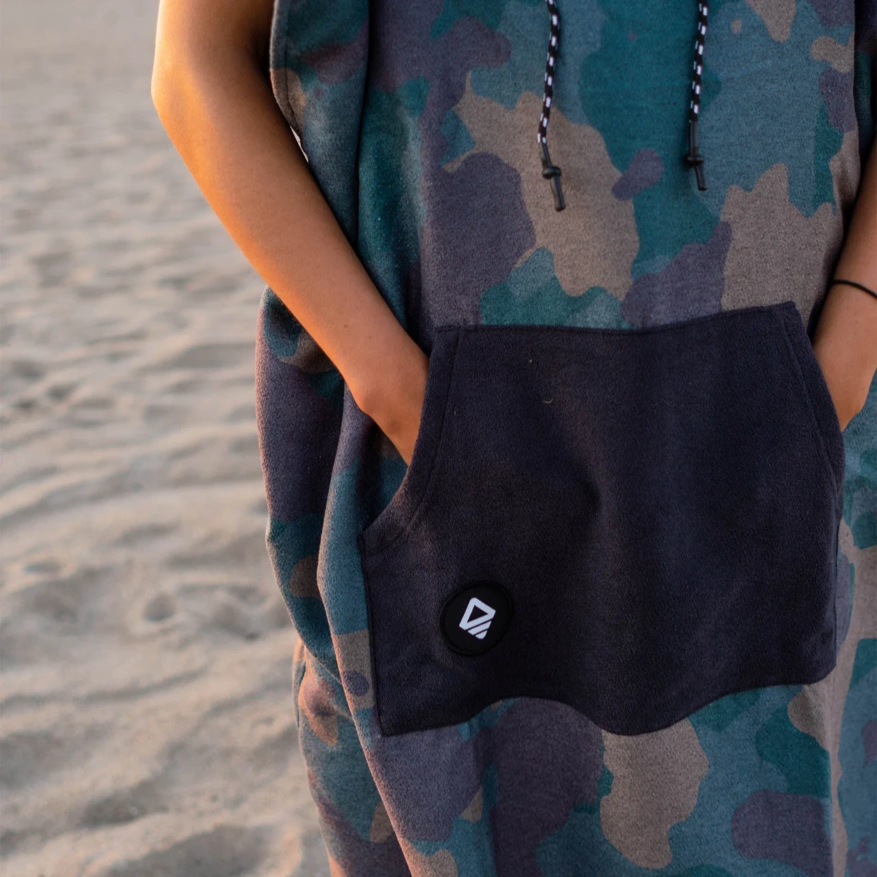 Front view of the Nomadix Camo Green Changing Poncho with drawstring hood and front pocket