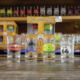 A souvenir four piece shot glass set arranged on a wooden retail gift shop shelf in front of product packaging