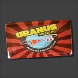 A rectangular souvenir magnet for "Uranus, Missouri" featuring a red and brown sunburst background. A central circular graphic shows a cartoon rocket ship orbiting a planet next to a "Historic Route 66" shield, with the playful slogan "Probe and Explore Uranus" printed along the bottom curve.