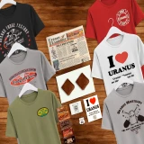A flat-lay collage on a wooden background displaying a massive Uranus souvenir bundle, featuring six different humorous graphic t-shirts—including "I Heart Uranus" and "Uranus Mortuary"—arranged around a local newspaper, two pieces of fudge, a magnet strip, and a collection of small Route 66 trinkets.