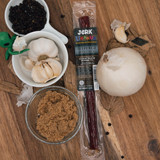 Peppered beef stick package surrounded by brown sugar, black peppercorns, and garlic from Uranus Fudge Factory.