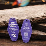 Front and back of a purple Inn Uranus vintage motel keychain displayed on wood from Uranus Fudge Factory.